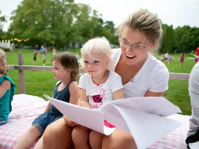 A mother reading to her child while sitting outside