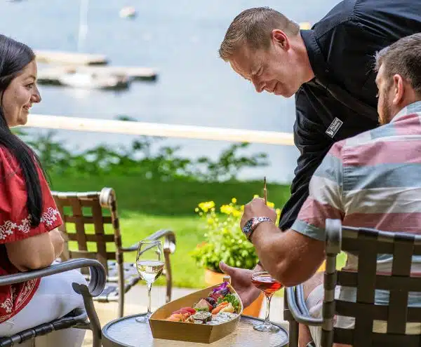 A server brining two guests some sushi out on the lodge porch.