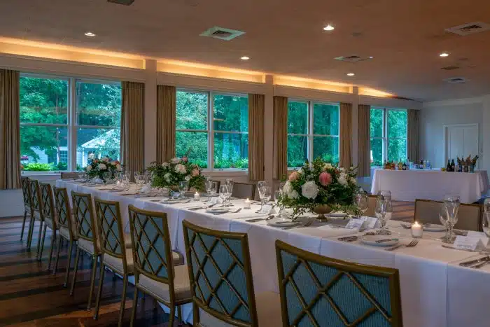 A room set up for an event with family style tables and a bar in the far right corner