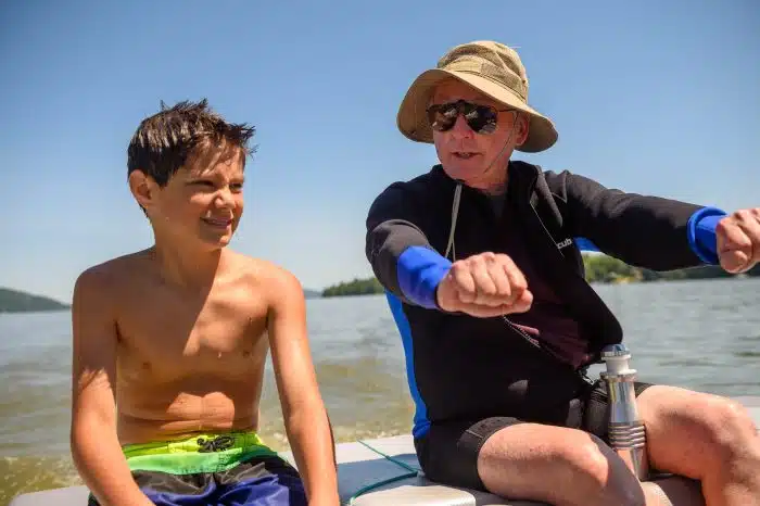 A family member teaching a young kid how to participate in a water sport