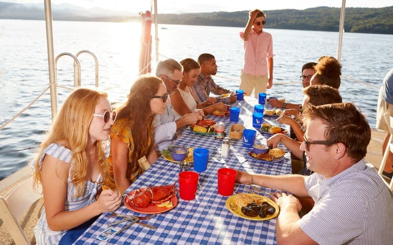 Group eating lobster and seafood dinner on the North Dock during golden hour.