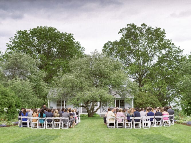 Group sits in the Orchard Garden waiting for a wedding ceremony to begin.
