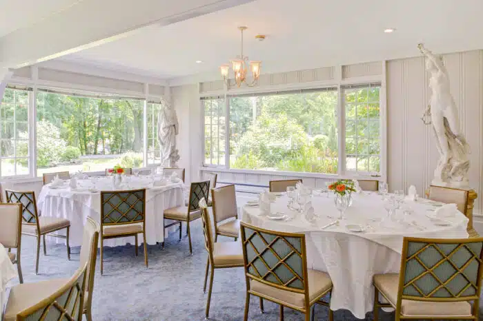 Round tables with cheerful flower arrangements in the Garden Room in Ardelia's venue