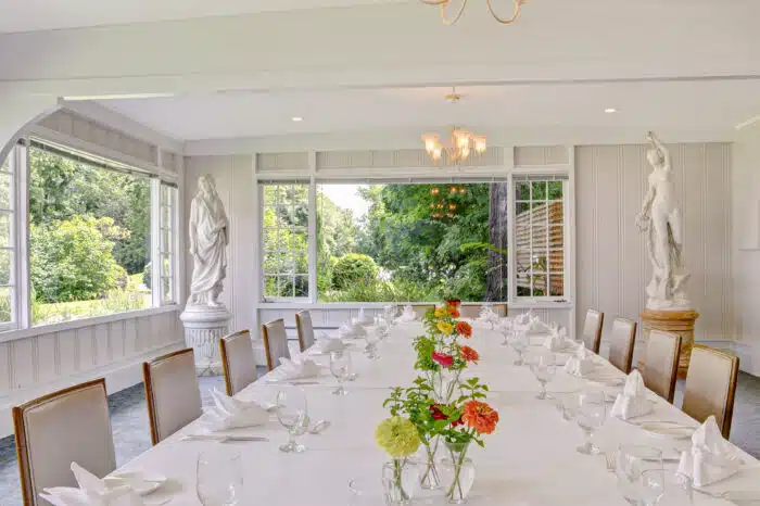 Family style table with cheerful flower arrangements in the Garden Room in Ardelia's venue