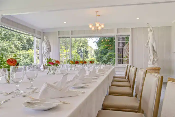 Family style table with cheerful flower arrangements in the Garden Room in Ardelia's venue