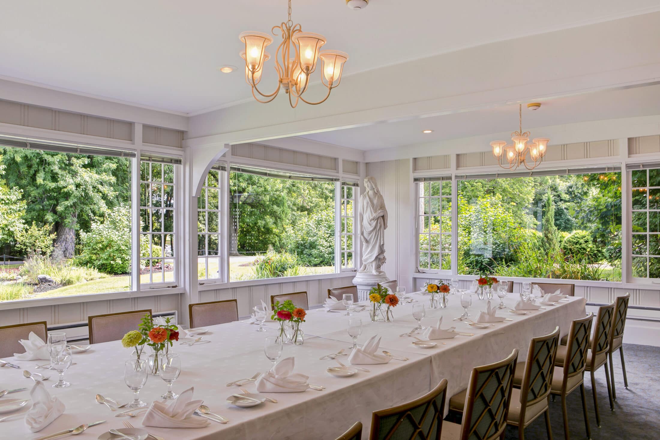 Family style table in the Garden Room with large windows overlooking the lush Chef's Garden