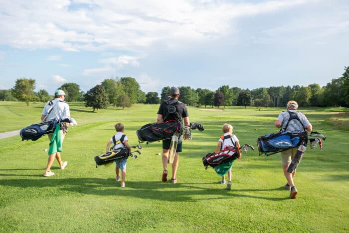 Family golf outing. Two young boys next to their fathers and grandfather prepare to play a round.