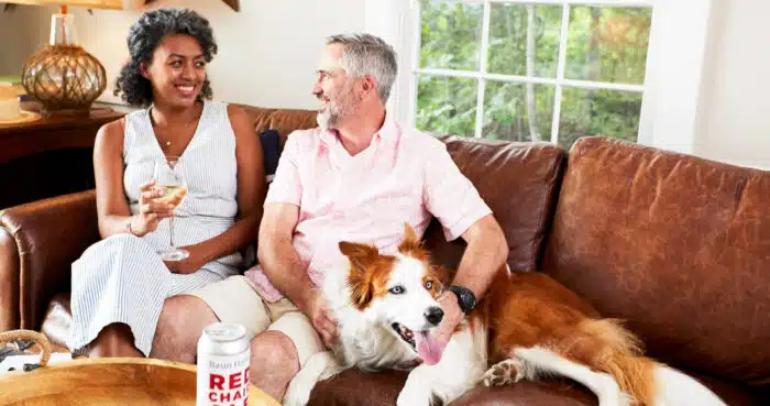A couple sitting on a couch with their dog