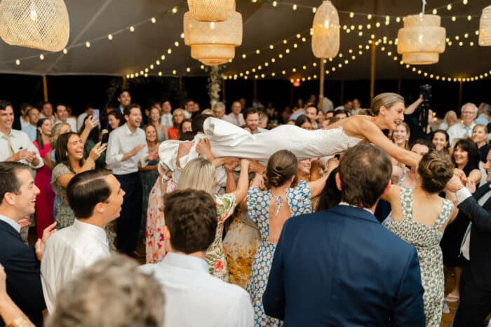 A wedding reception party where the bride is crowd surfing