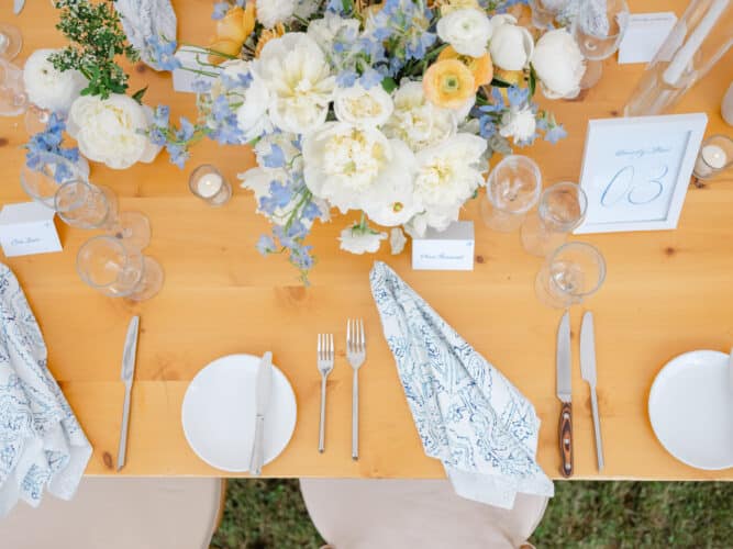 Beautiful tablescape with full floral arrangements of white peonies, blue accents and peach colors ranunculus