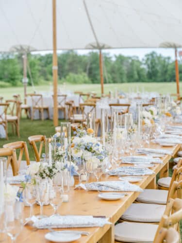 Tented wedding reception at Basin Harbor, set with bright whites and blue floral accents