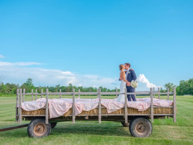 A bride and groom kissing on a hay wagon