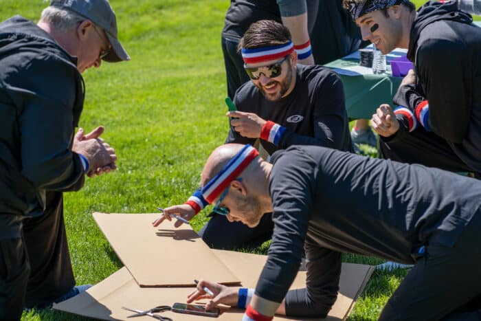 Cardboard challenge for team building. Group with sweatbands figure out their challenge.