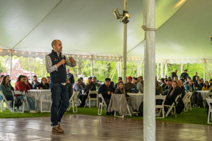 Award ceremony under a tent with man with microphone addressing the group.