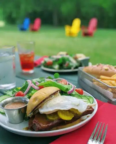 A close up of a burger with a side salad