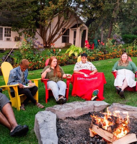 A group of people sitting in front of a campfire making s'mores