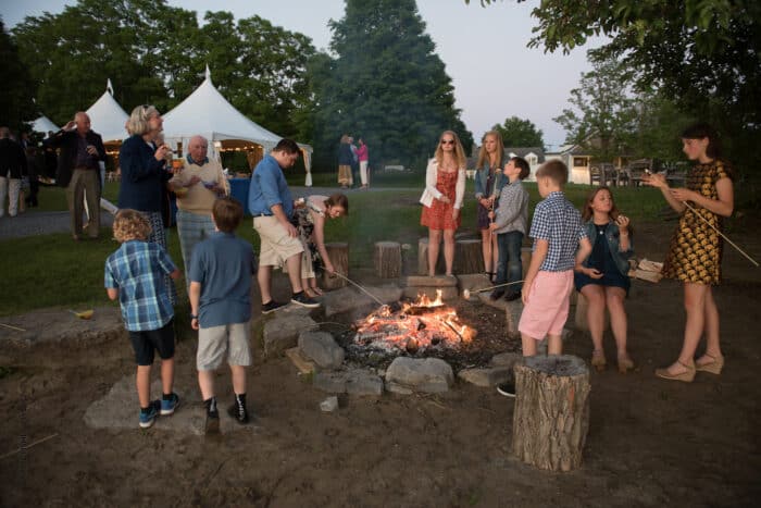 A group of people gathered around a campfire cooking S'Mores