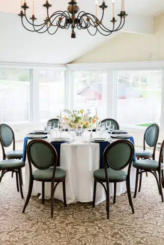 A round table with a yellow and pink flower centerpiece set up for a wedding.
