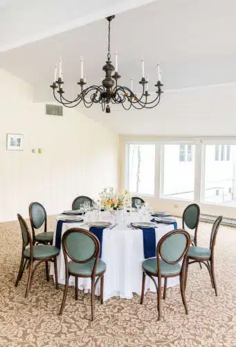 A round table with a yellow and pink flower centerpiece set up for a wedding.