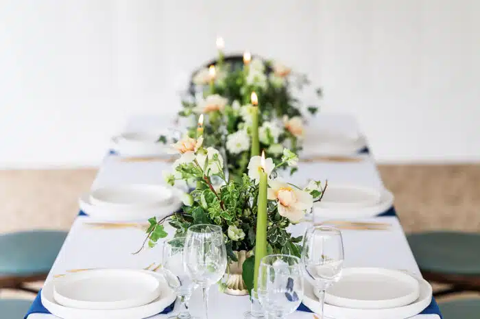 A close up of the flowers and candle centerpieces on a long rectangular table.