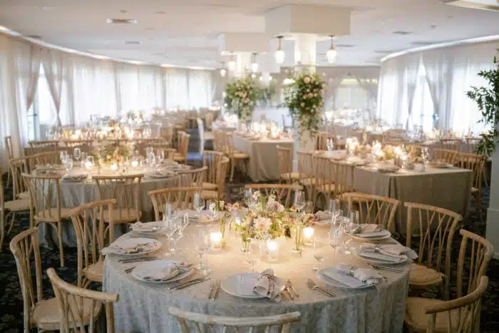 The main dining room decorated for a wedding with floral arrangements attached to the four floor to ceiling pillars. The dining tables are draped in a white and gold tablecloth.