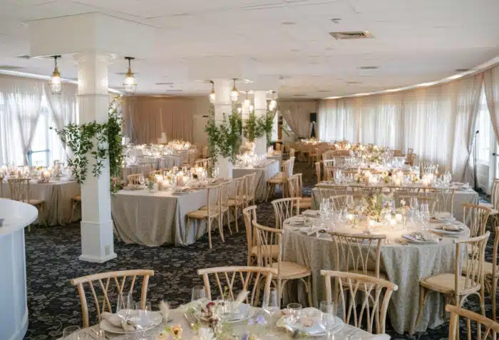 The main dining room decorated for a wedding with floral arrangements attached to the four floor to ceiling pillars. The dining tables are draped in a white and gold tablecloth.