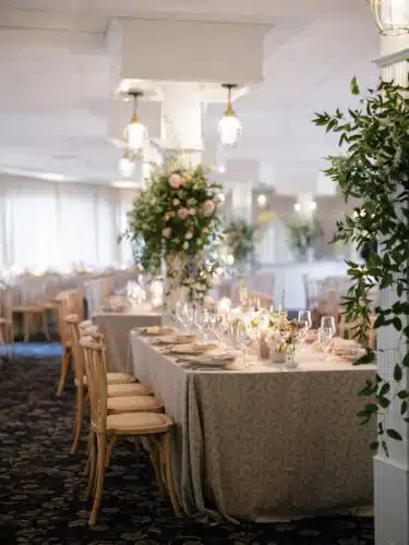 The main dining room set for a wedding with flower baskets hanging from pillars.