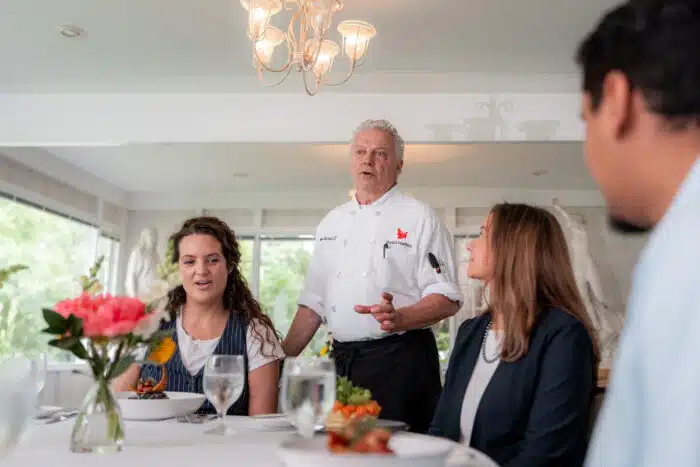 A chef speaking with a group of guests at a dinner table