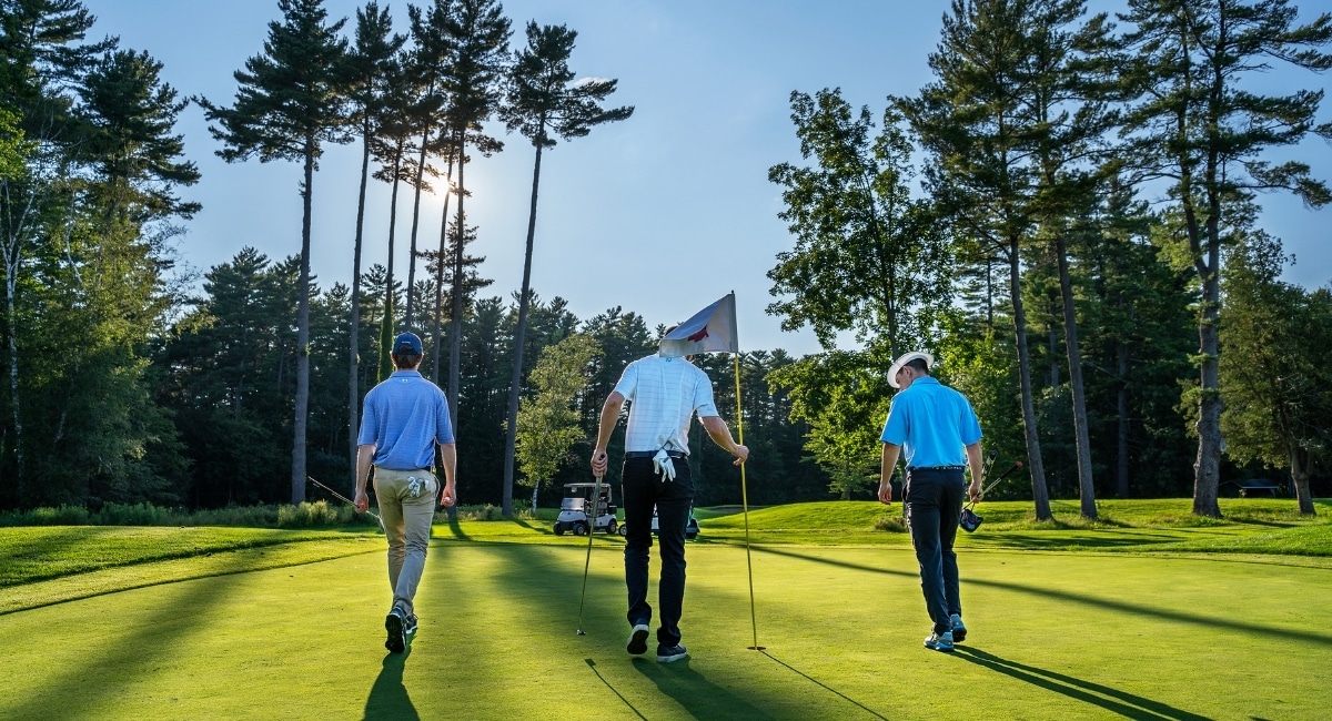 A group of golfers walking the green on a sunny morning.