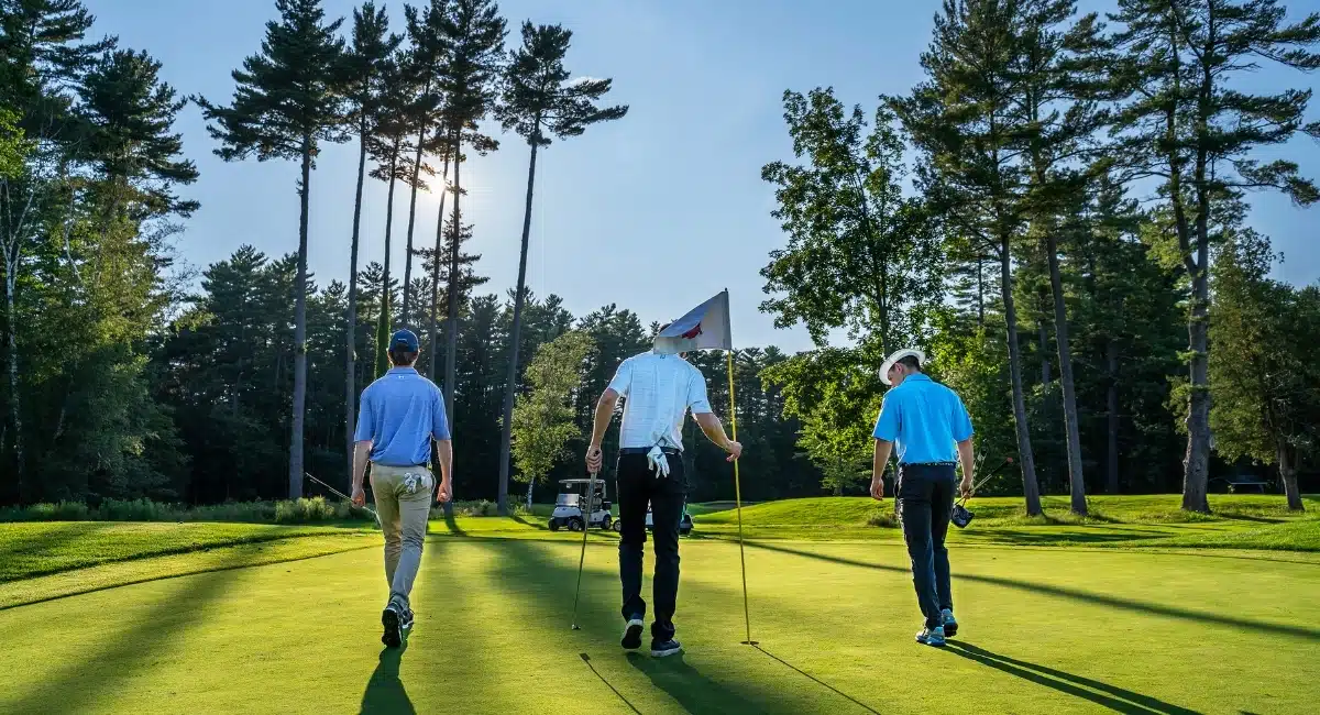 Three men finishing a put on the golf course