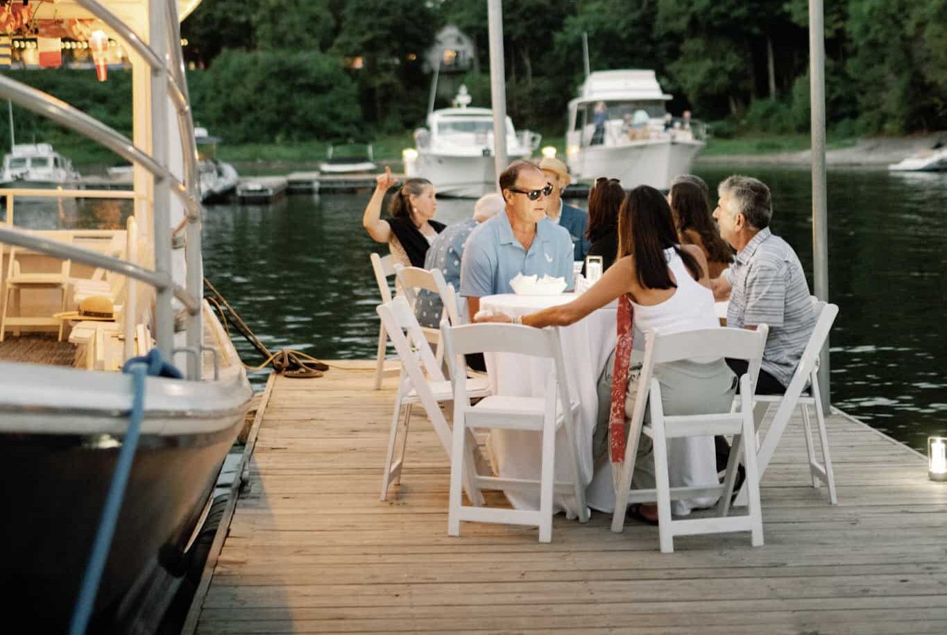 Group of dock goers sitting in some chairs on the boat docks with drinks in hand